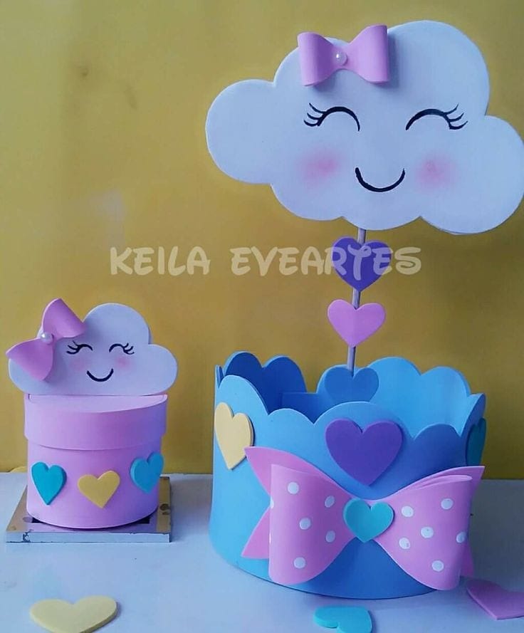 Centro de mesa em EVA com nuvem sorridente, corações coloridos e lacinho rosa, decorado em tons pastel para festa infantil com tema Chuva de Amor.