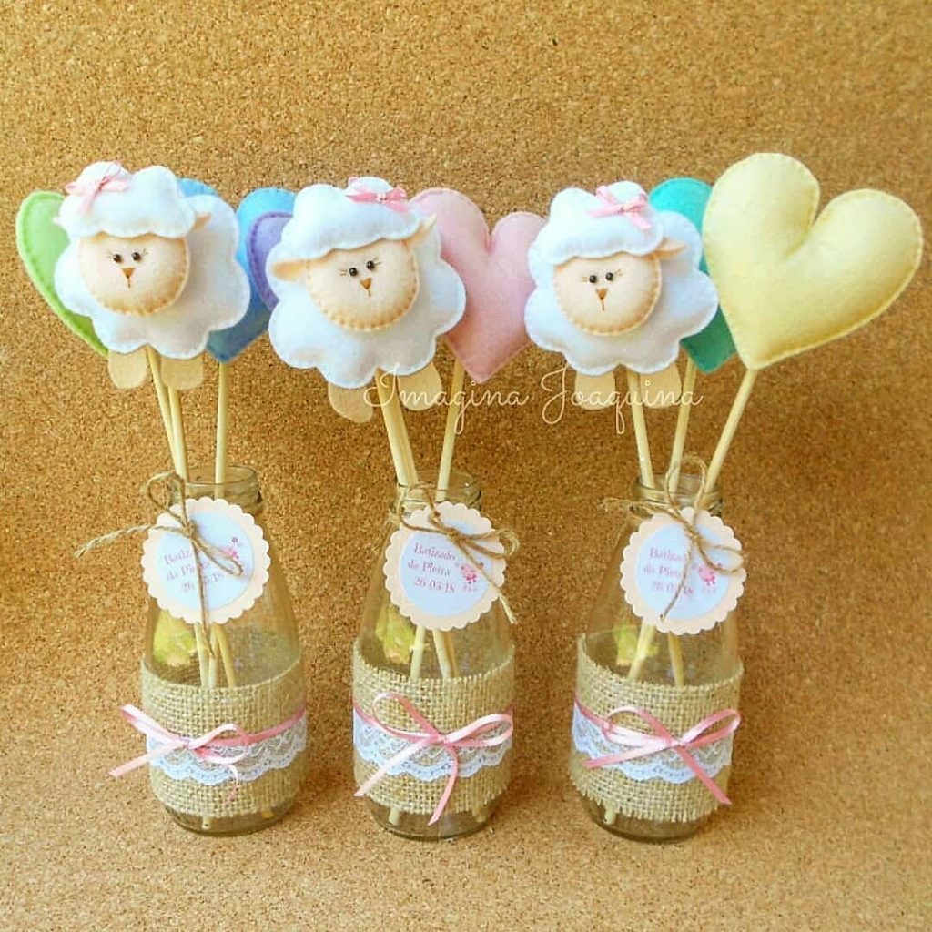 Garrafinhas decoradas com juta e renda, com apliques de ovelhinha e corações de feltro, usadas como centro de mesa para batizado ou festa infantil delicada.