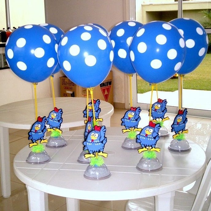 Centro de mesa infantil com balão azul de poá e Galinha Pintadinha em base decorada.