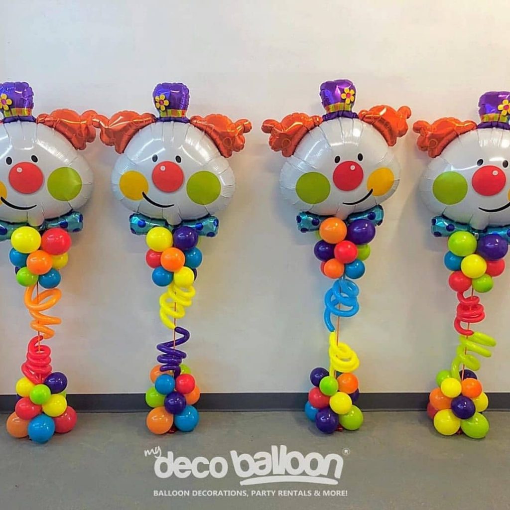 Centro de mesa com balões coloridos e balão foil em formato de rosto de palhaço, ideal para decoração de festa infantil temática de circo.