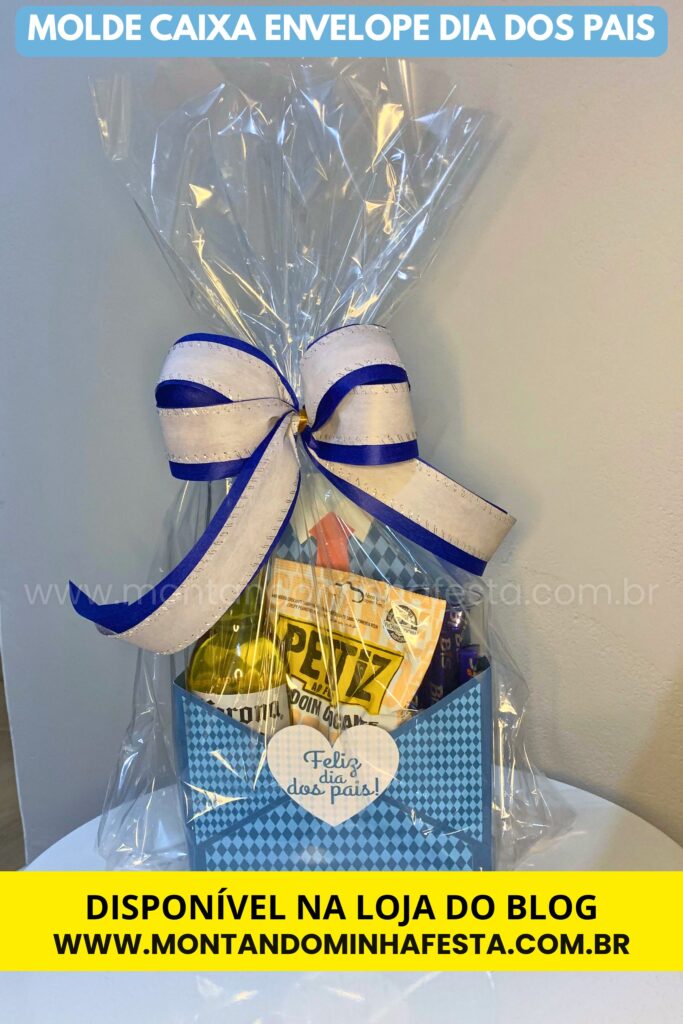 Caixa envelope Dia dos Pais com estampa azul e detalhe de coração com a frase “Feliz dia dos pais!”, embalada em celofane transparente com laço azul e branco, ideal como embalagem criativa para presentear; molde disponível na loja do blog Montando Minha Festa.