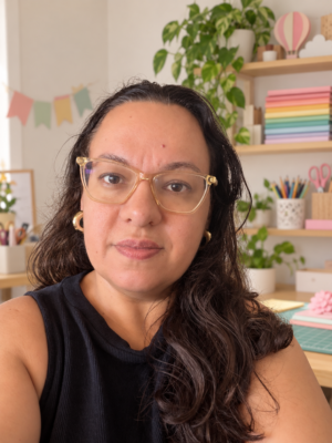 Angélica Zamonelo, criadora do blog Montando Minha Festa, com fundo de ateliê de papelaria.